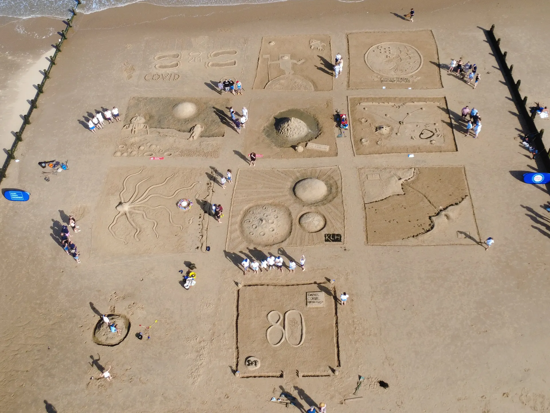 Aerial image of sandcastles laid out as a grid on golden sands 